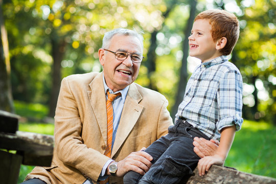 Grandfather and grandson are sitting and talking in park