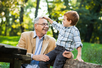 Grandfather and grandson are sitting and talking in park