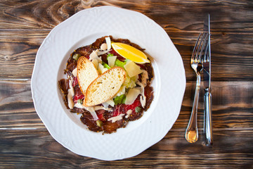 Salad with slices of smoked meat and vegetables on a white plate