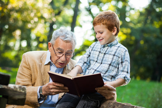 Grandfather and grandson are reading book and learning about nature