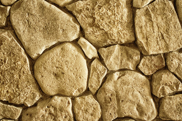 background texture of a wall lined with natural stone close-up, toned photo