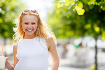 Cute blonde woman in park in bright summer day