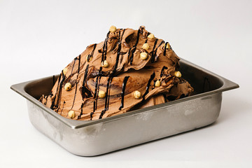 Chocolate ice cream with hazelnuts in the metal tray on white background