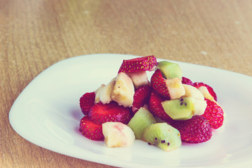 Healthy fruit salad with chocolate and yougurt in white dish. Healthy breakfast, weight loss concept