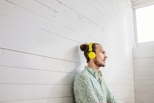 Man with headphones sitting at white wooden wall