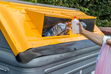 man putting plastic waste in recycling bin