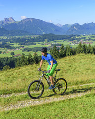 Obraz premium Mountainbiker radlet auf einem Bergrücken mit toller Aussicht im Allgäu