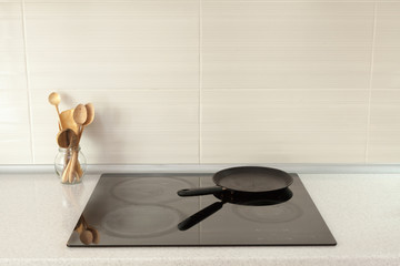 Cooking pan wooden spoons in modern kitchen with induction stove