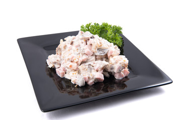 Salad with fish, mushrooms and mayonnaise, decorated by parsley on white background