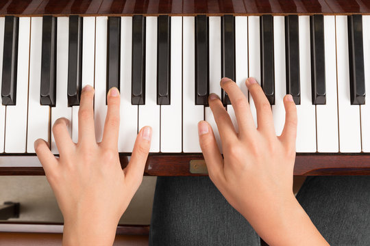 Top view close up of female hands playing piano