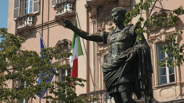 Ancient Augustus emperor statue in front of Italian and European flag in Pavia, Italy
