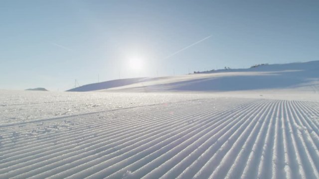 CLOSE UP: Perfectly groomed  piste snow in sunny ski resort 
