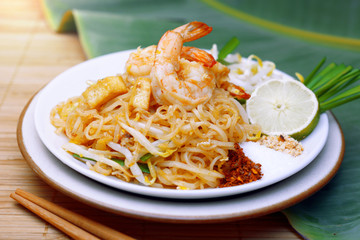 Famous traditional thai food shrimp pad thai, rice noodle stir-fry with prawns, tofu and vegetables on wooden background.