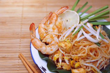 Famous traditional thai food shrimp pad thai, rice noodle stir-fry with prawns, tofu and vegetables on wooden background.
