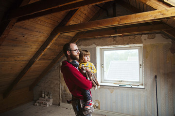 Father and daughter standing in attic under renovation