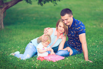Fototapeta premium Happy family of three lying in the grass .
