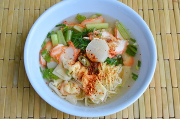 Chinese egg noodle with barbecue pork and dumpling in clear soup dressing chili on bowl