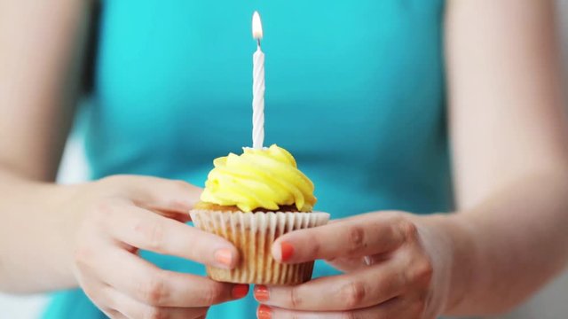 woman with burning candle on birthday cupcake