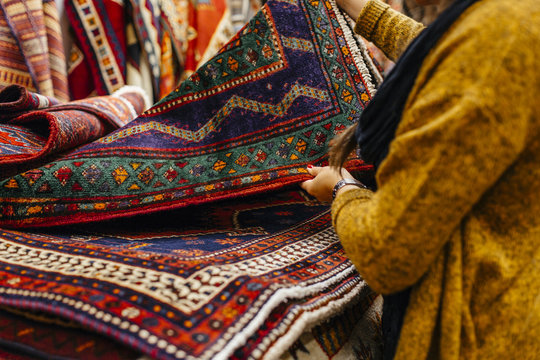 Midsection of young woman shopping for rugs in furniture warehouse