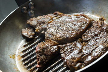 Grilling steak on grill pan. Beefsteak cooking on a kitchen. Fresh, delicious, spicy, juicy meat with copy space closeup.