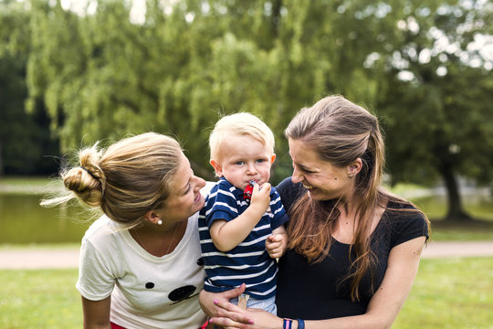Two smiling women with toddler outdoors