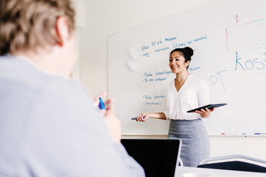 Businesswoman giving presentation to colleague in conference room
