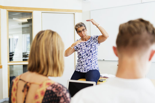 Mature female professor teaching students in classroom