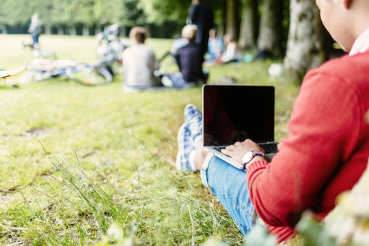 Rear view of university student using laptop at park