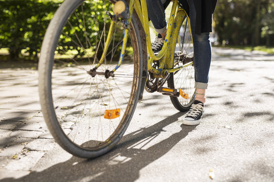 Low section of young woman riding bicycle on street
