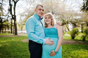 Fototapeta premium Happy pregnant couple hugging in nature background spring blossom tree