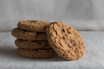 Cookies pile with chocolate chip on light textile background. Delicious morning snacks for breakfast, brunch and lunch. Appetizing, healthy, sweet, scrummy, and fast food.