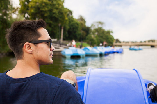 Rear view of man pedal boating on river in city