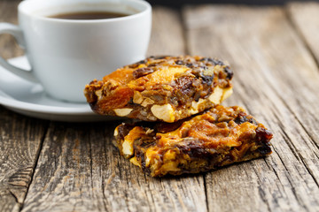 Tasty vegetarian granola cake slice with coffee on wooden table.