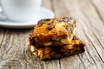 Tasty vegetarian granola cake slice with coffee on wooden table.
