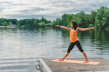 Fototapeta na wymiar Young woman doing yoga on the lake