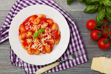Serving gnocchi in tomato sauce with cheese.