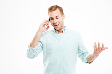 Cheerful attractive young businessman standing and talking on cell phone