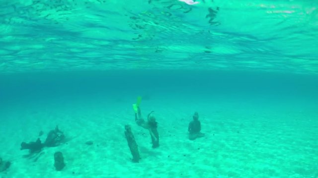 SLOW MOTION: Woman snorkeling underwater exploring statues on sea bottom