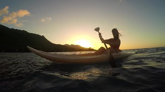 SLOW MOTION: Young woman kayaking on ocean at golden sunset