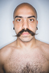 Studio portrait of young mid adult man with mustache looking at camera - beard care, wellness...