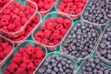 Fresh blueberry and raspberry in plastic box at market