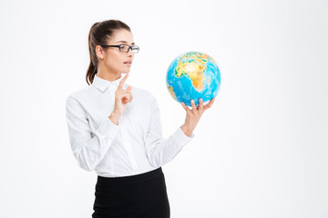 Thoughtful beautiful young businesswoman holding globe and thinking