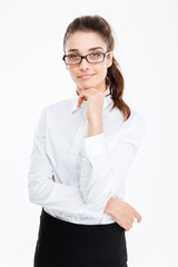 Pensive pretty young businesswoman in glasses standing and thinking