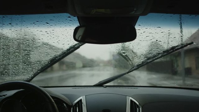 SLOW MOTION: Wiping raindrops off a windshield in a car