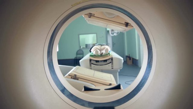 Unrecognizable hospital patient lying on MRI, tomograph, scanner, moving to and from the camera. Slider shoot. 1080p.