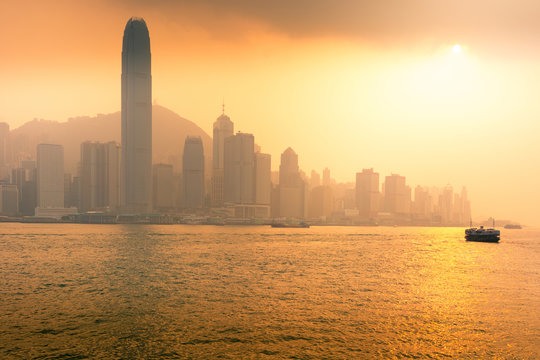 Hong Kong business district with sunset and sailing boat.
