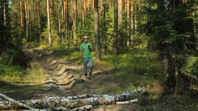 A man walks through the forest with the phone and looks at the navigation application. He chooses the right direction