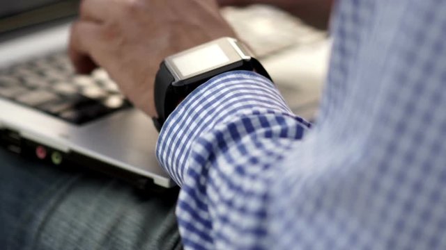 Close up of man check his smart watch with laptop
