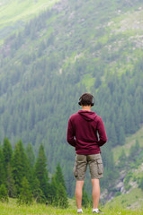 Fototapeta na wymiar Back of teenager listen to music at headphones on mountain