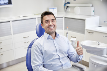 Fototapeta premium happy man showing thumbs up at dental clinic